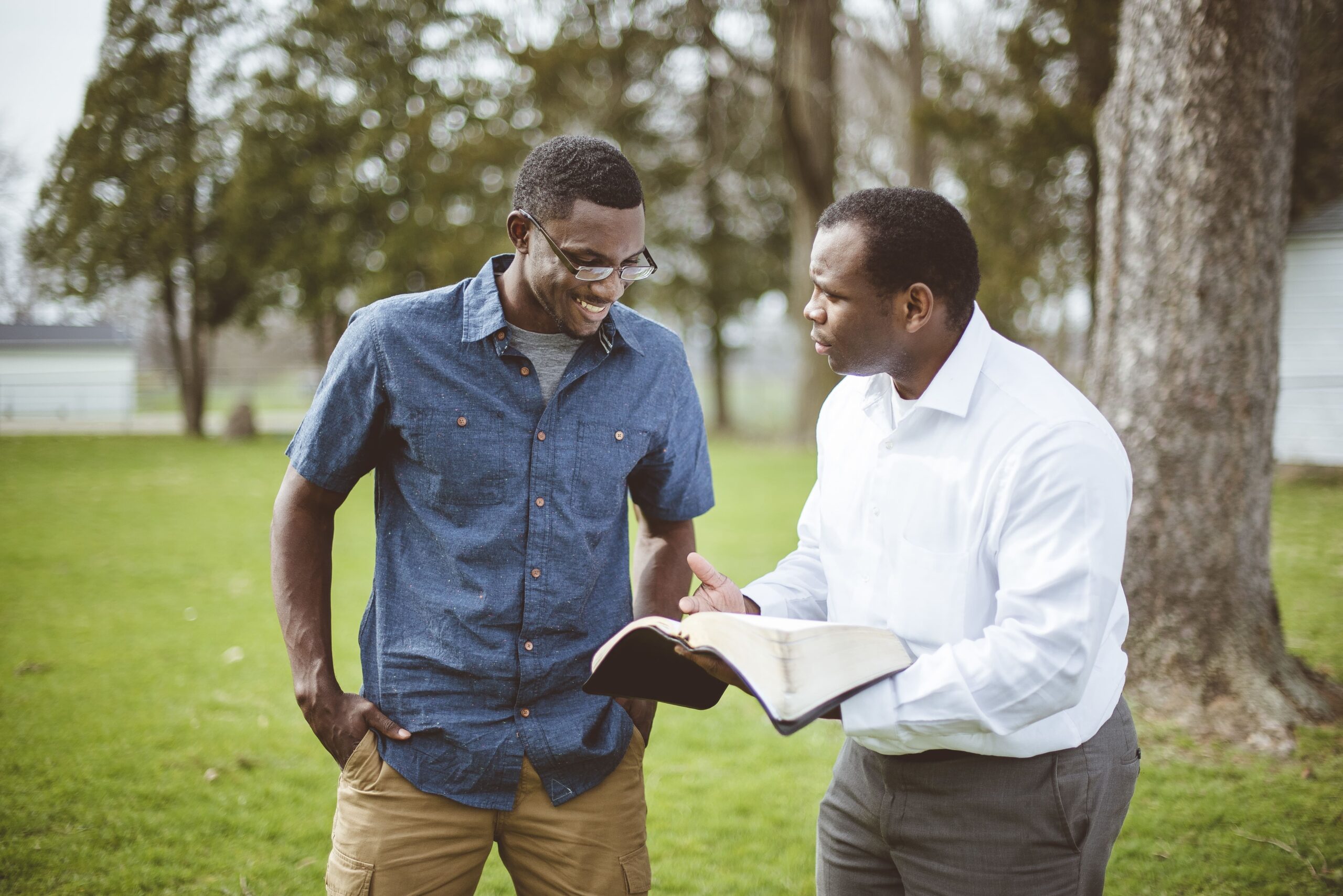 african american male friends standing park discussing bible (1)